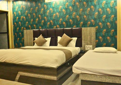 two beds in a hotel room with a wallpaper at Ganga Riverfront Rooms And Banquet in Prayagraj