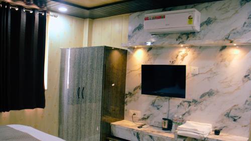 a room with a tv on a marble wall at Ganga Riverfront Rooms And Banquet in Prayagraj