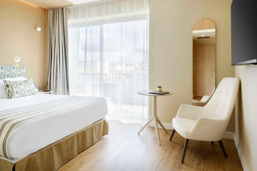 a hotel room with a bed and a chair and a window at Barceló Illetas Albatros - Adults Only in Illetas
