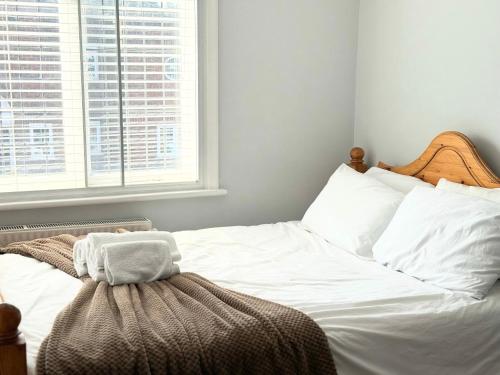 a bedroom with a bed with white sheets and a window at Entire Cosy Flat in Radlett - 3 Bedrooms -5 Beds - Sleeps 8 - Fast Train access into central London in Radlett