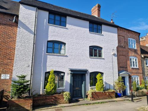 a white brick house with a blue door at Ludlow - Linnet House - Well Presented Townhouse With Parking - Perfect Location For Exploring On Foot, Sleeps Up To 8 Guests - Hosted by RENTMYHOUSE in Ludlow