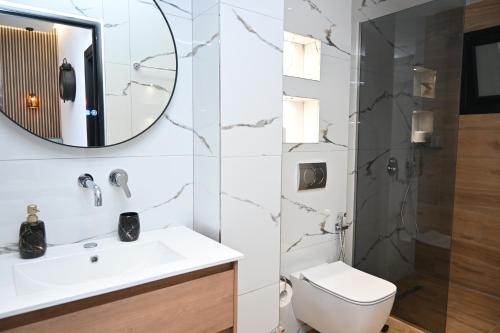 a bathroom with a toilet and a sink and a mirror at Vila La Familia in Ksamil