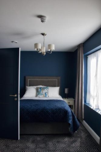 a blue bedroom with a bed and a window at The Monks Quarters in Quin