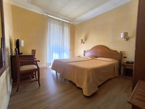 a bedroom with a bed and a desk and a window at Mariano IV Palace Hotel in Oristano