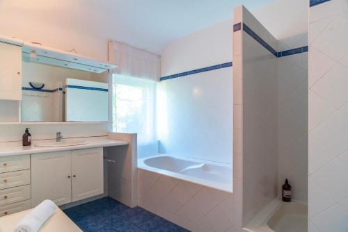 une salle de bain blanche avec une baignoire et un lavabo dans l'établissement Kerlavarec - Belle maison avec grand jardin, à Locmariaquer