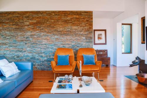 a living room with two chairs and a brick wall at Just Like Home - Casa do Caracol Horizon Retreat in Viana do Castelo