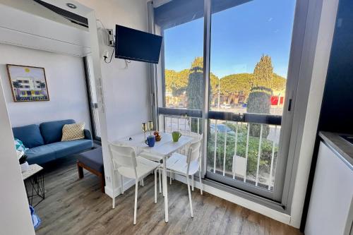 un salon avec une table et une grande fenêtre dans l'établissement LE CABESTAN - studio proche plage, au Grau-du-Roi