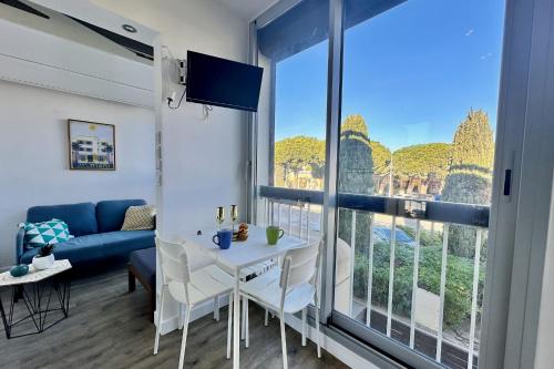 un salon avec une table et une grande fenêtre dans l'établissement LE CABESTAN - studio proche plage, au Grau-du-Roi