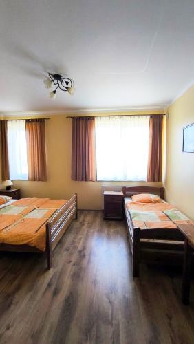 two beds in a large room with two windows at Jaś i Małgosia nad Jeziorem Wigry in Rosochaty Róg