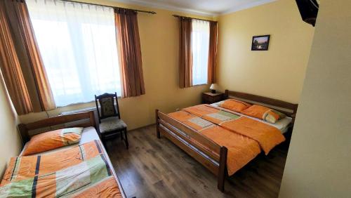 a bedroom with two beds and a chair and windows at Jaś i Małgosia nad Jeziorem Wigry in Rosochaty Róg