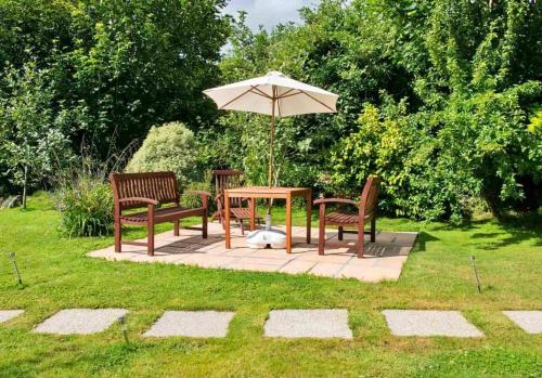 a table and chairs with an umbrella in the grass at Finest Retreats - Orchard View in Hayle