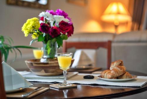 a table with a glass of orange juice and a vase of flowers at Finest Retreats - Orchard View in Hayle