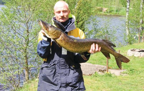 a man holding a fish in his hand at Cozy Home In Gislaved With Lake View in Våthult