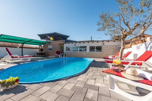 a swimming pool with two chairs and a table at Villa Luma ZadarVillas in Gorica