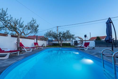 een zwembad met stoelen en parasols op een patio bij Villa Luma ZadarVillas in Gorica