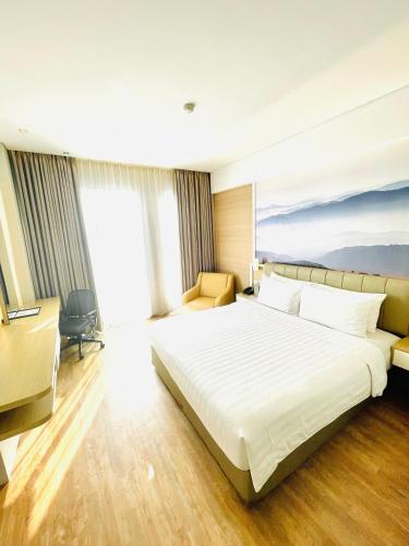 a bedroom with a large white bed and a large window at Horison Tasikmalaya in Tasikmalaya