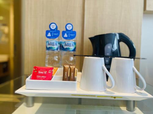 a shelf with two white mugs and a coffee maker at Horison Tasikmalaya in Tasikmalaya