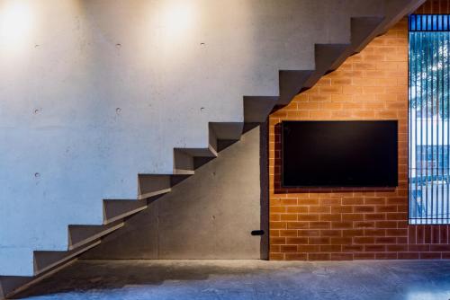 a staircase with a television on a brick wall at Camperdown- Luxury Architectural Apartment Escape in Sydney