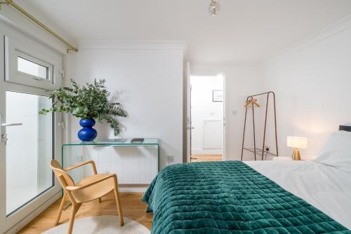 a bedroom with a green bed and a chair at Niru Experience Stylish Garden Getaway in London