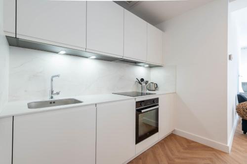 une cuisine blanche avec un évier et une cuisinière dans l'établissement 3-Br apartment in the Golden Square, à Cannes