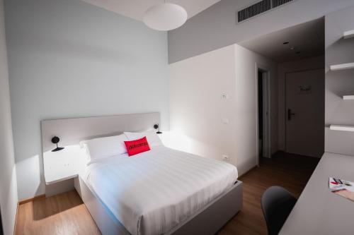 a bedroom with a white bed with a red pillow at Dotcampus Roma City Center in Rome