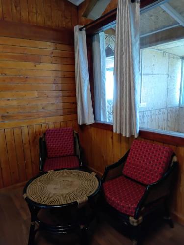 a room with two chairs and a table and a window at De Rock Jungle Living Resort in Coonoor