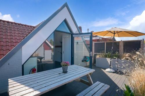 a wooden picnic table on a deck with an umbrella at Weststraat 22 - Ouddorp - Appartement Zuid 3P in Ouddorp
