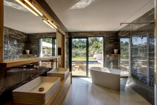 une salle de bain avec baignoire et une grande fenêtre dans l'établissement La Villa Luxury Green patio, à Cirendinu