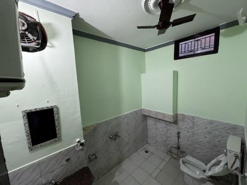 a bathroom with a toilet and a tv on the wall at Vedic Stays Haridwar in Haridwār