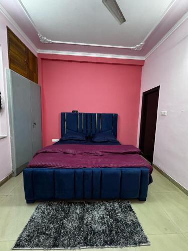 a bed in a room with a pink wall at Vedic Stays Haridwar in Haridwār