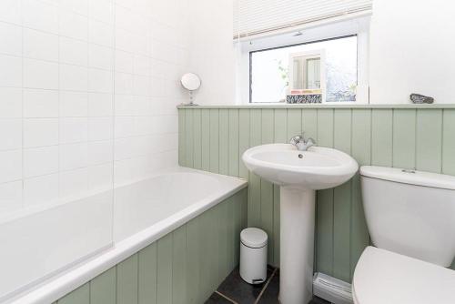- une salle de bains verte et blanche avec lavabo et toilettes dans l'établissement Miners Cottage, à Blaenau Ffestiniog