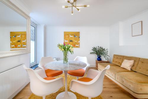 a living room with a table and chairs and a couch at Niru Experience Stylish Garden Getaway in London