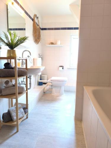 a bathroom with a tub and a toilet and a sink at FeWo Nesthäkchen-Erholung in Historischer Villa an der Nordsee in Dornum
