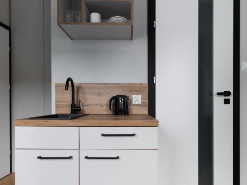 a kitchen with white cabinets and a sink at Hotel Kozerki in Kozerki