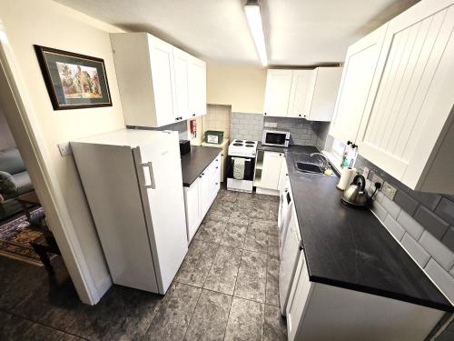 a kitchen with white cabinets and a white refrigerator at North Lodge North in Knebworth