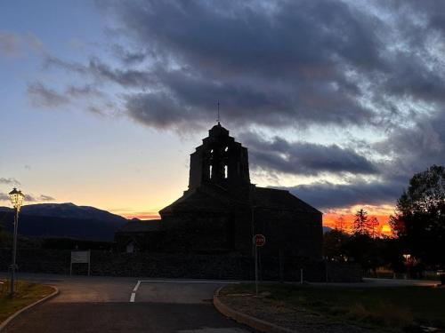 a building with a clock tower in the sunset at L'avet blau in Sainte-Léocadie