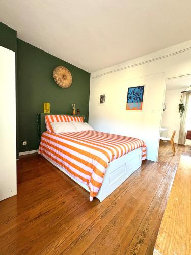 - une chambre avec un grand lit et une couverture rayée dans l'établissement Appartement Clim Wifi Tendance, à Avignon