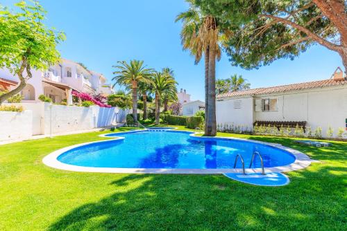 a swimming pool in a yard with palm trees at UHC CasasBlancas Family Complex in Salou