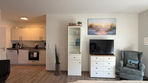 a living room with a television and a kitchen at App2-SD9 Dieksand in Friedrichskoog