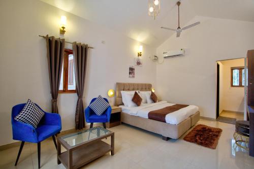 a bedroom with a bed and a blue chair at Close2C By The Arks Villa in Anjuna