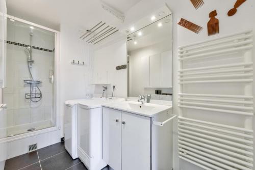 une salle de bain blanche avec un lavabo et une douche dans l'établissement Stunning Parisian 1BR Flat near the Eiffel Tower, à Paris