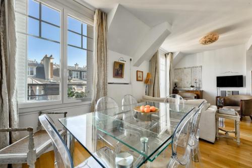 une salle à manger avec une table et des chaises en verre dans l'établissement Stunning Parisian 1BR Flat near the Eiffel Tower, à Paris