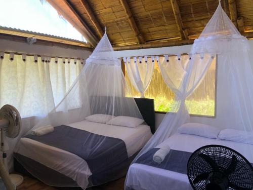 two beds in a bedroom with mosquito nets at Zirumake Tayrona Dentro del Parque Tayrona in El Zaino