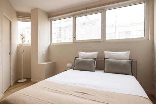 une chambre avec un grand lit avec deux fenêtres dans l'établissement Studio calme proche de Paris 19 - V, à Le Pré-Saint-Gervais