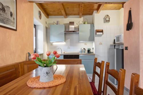 a kitchen with a wooden table with a vase of flowers at Petite Maison Tillier in Fenis