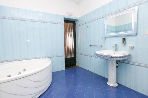 a blue bathroom with a tub and a sink at Villa Meminaj in Vlorë