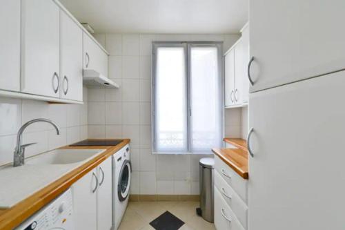 une cuisine blanche avec un évier et un lave-vaisselle dans l'établissement The Cosy Cocon Close to Eiffel Tower & Invalides, à Paris