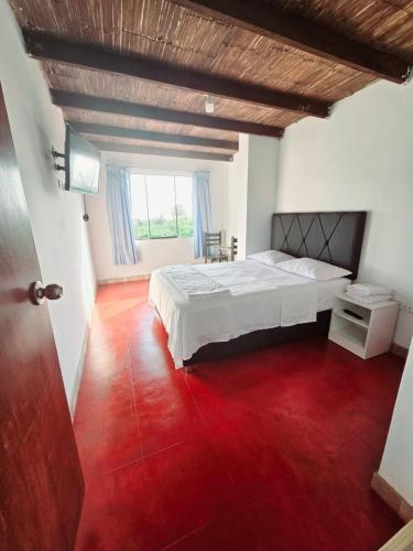a bedroom with a white bed and a red floor at Los Angeles Hotel in Huaral