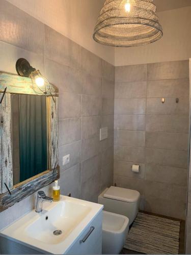 a bathroom with a sink and a toilet and a mirror at Casa Ambra in Specchiolla 
