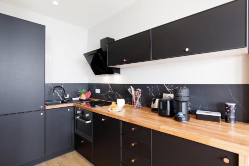 une cuisine avec des armoires noires et un comptoir en bois dans l'établissement La Terrazza - Palais des festivals et Croisettes, à Cannes